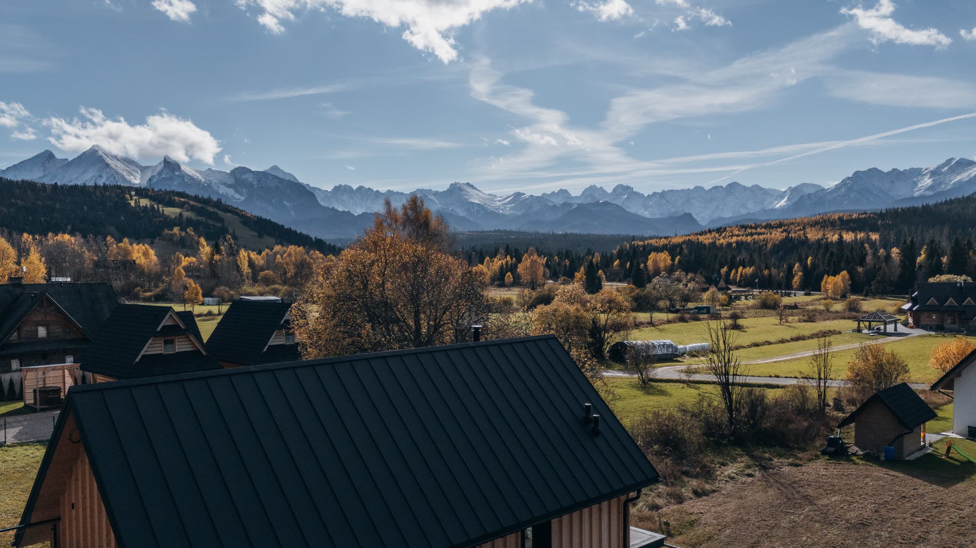 Jesienna panorama Tatr widziana z Jurgowa – pasmo Tatr Wysokich i Bielskich oraz drewniane domy spiskie